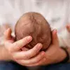 bébé dans les bras d'un parent