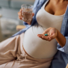 Femme enceinte qui tient une pillule (médicament) dans sa main