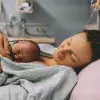femme sur un lit d'hôpital, allongée, tenant le bébé qu'elle vient d'accoucher, souriante